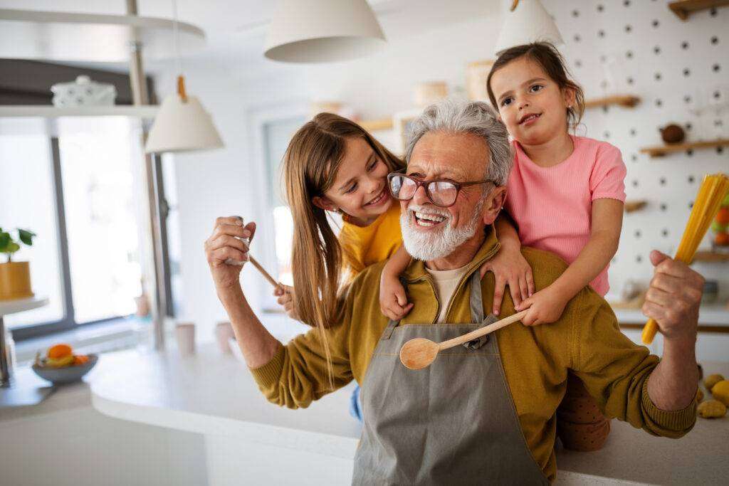 Grandfather with a joyful smile cooking with his granddaughters