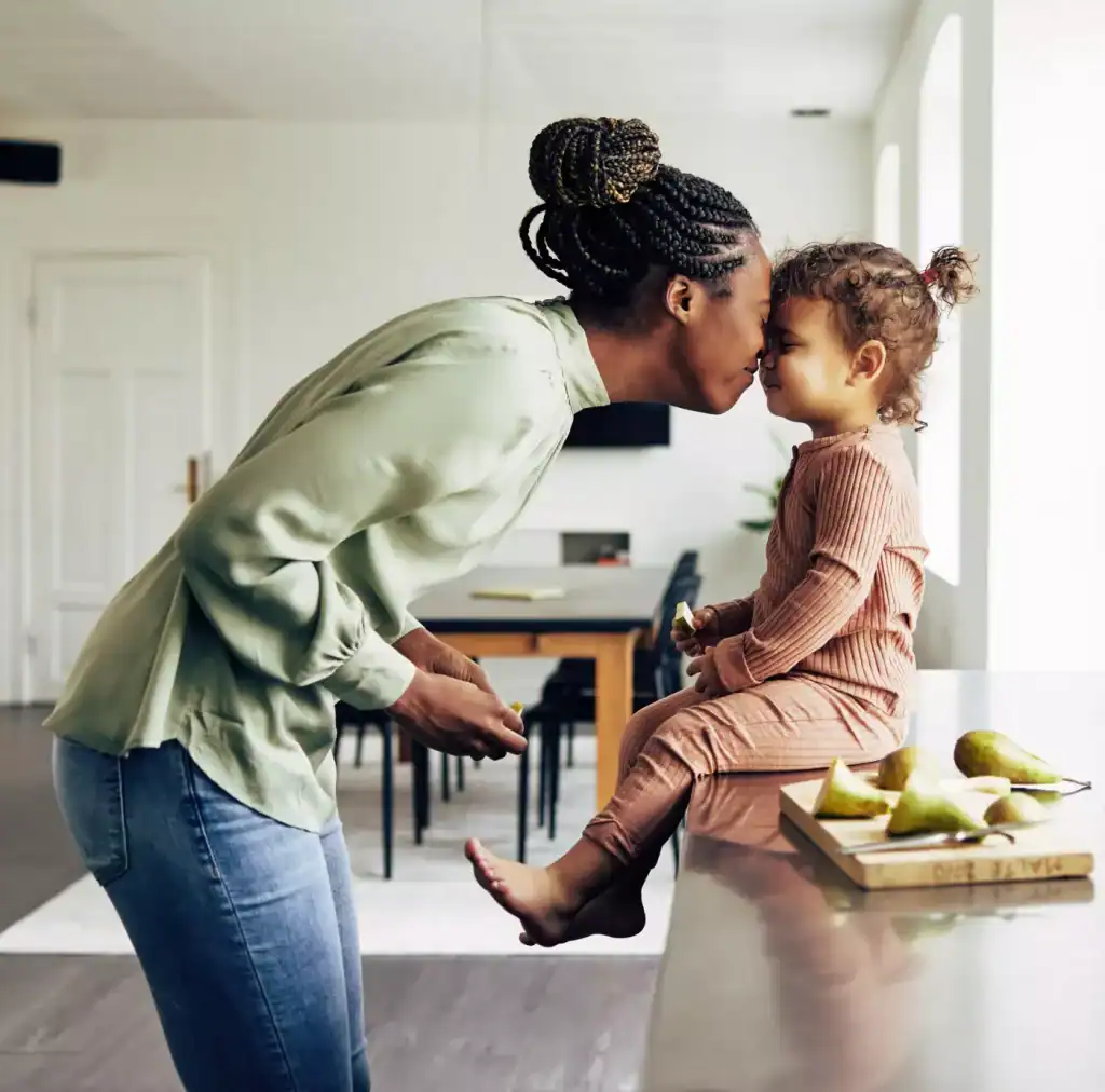 A mother gently kissing her toddler