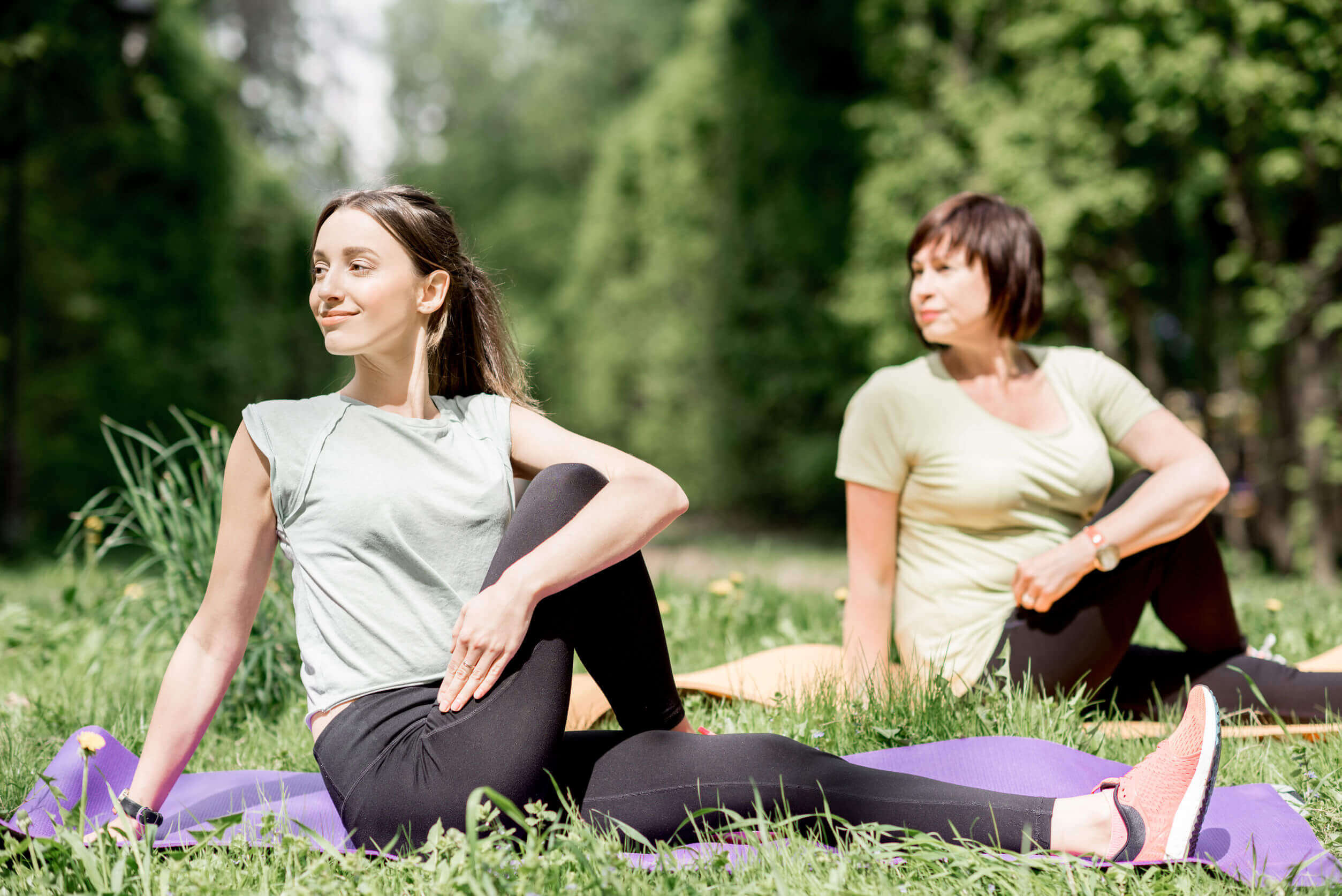 Two women practicing yoga outdoors, promoting health and balance of hormones.